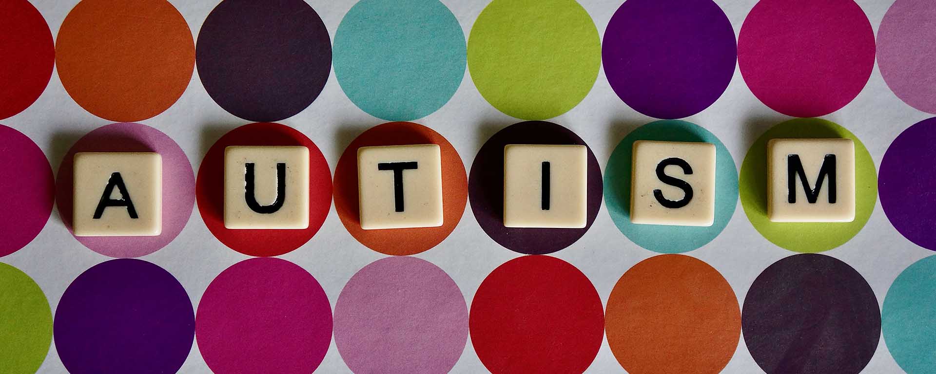 Bright circles background with word tiles on the top, which spell: Autism