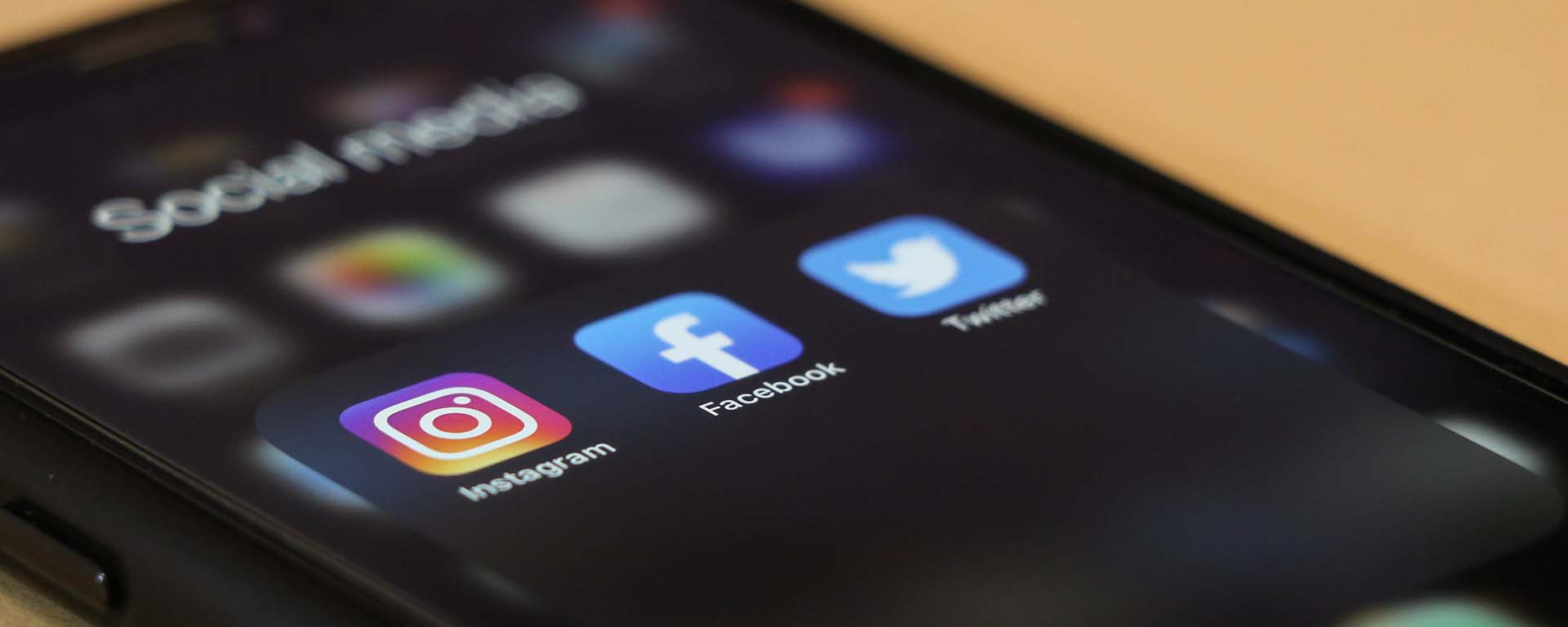 A mobile phone with Instagram, Facebook and Twitter apps showing on the homepage