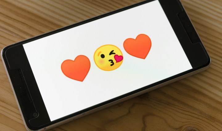A phone showing two love hearts and a kiss emoji