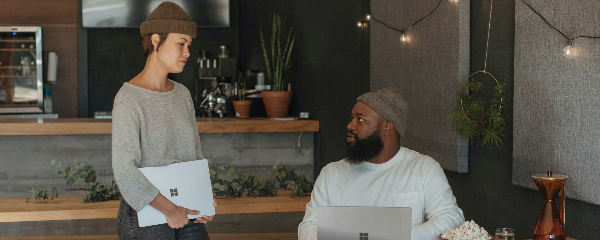 A woman stands and talks to a man who sits at a table