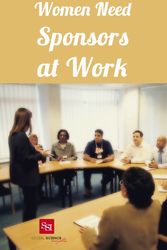 A woman speaks in front of colleagues who sit around a table