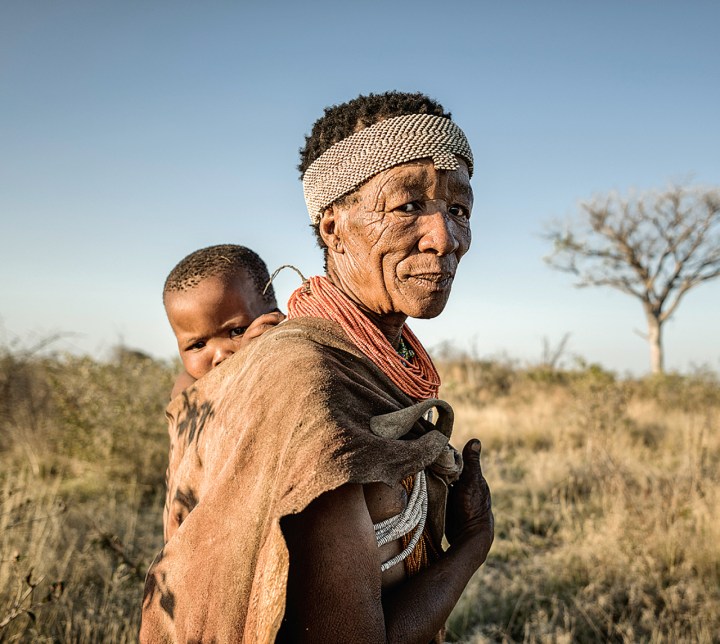 Ju/'hoansi woman carries a baby swaddled on her back