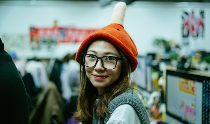 A woman wearing glasses and a beany looks and smiles