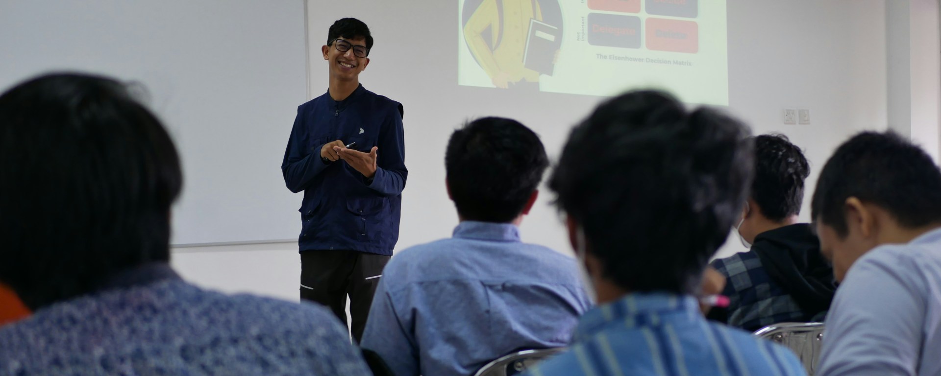 A man stands in front of a classroom smiling