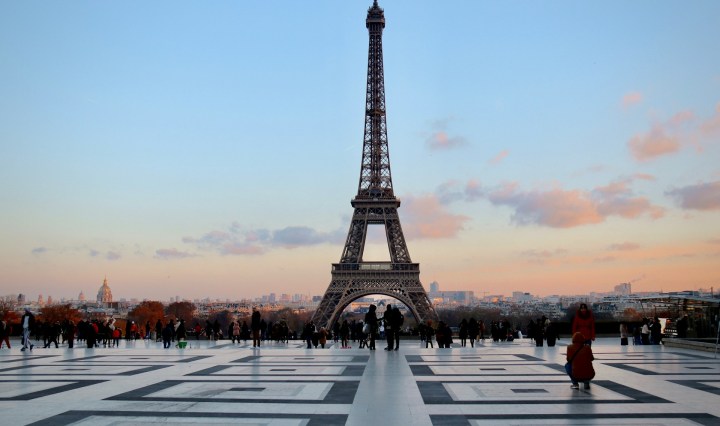 The Eiffel Tower stands in the background, as people take photos