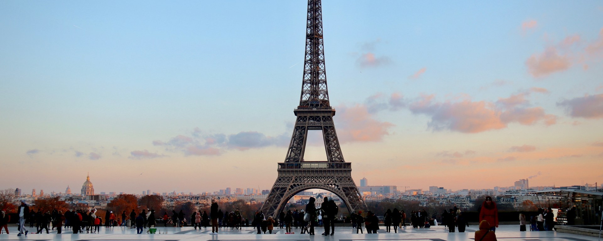 The Eiffel Tower stands in the background, as people take photos