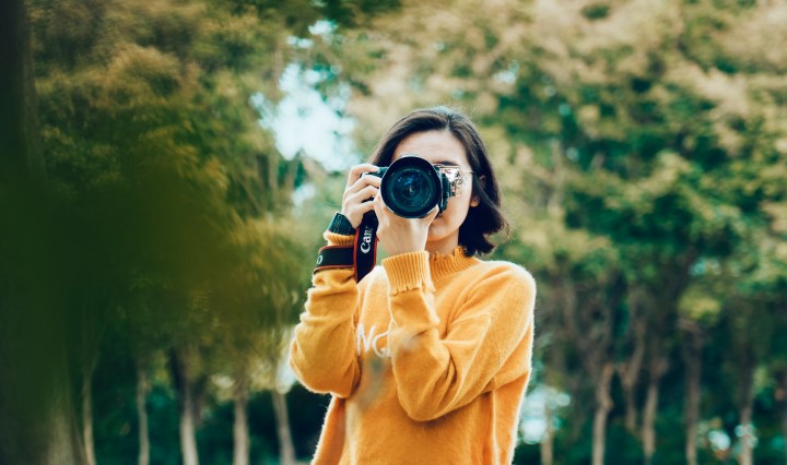 Woman looks through the lens of camera, outdoors
