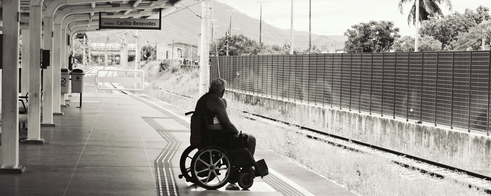 A man on a wheelchair waits on an empty train platform