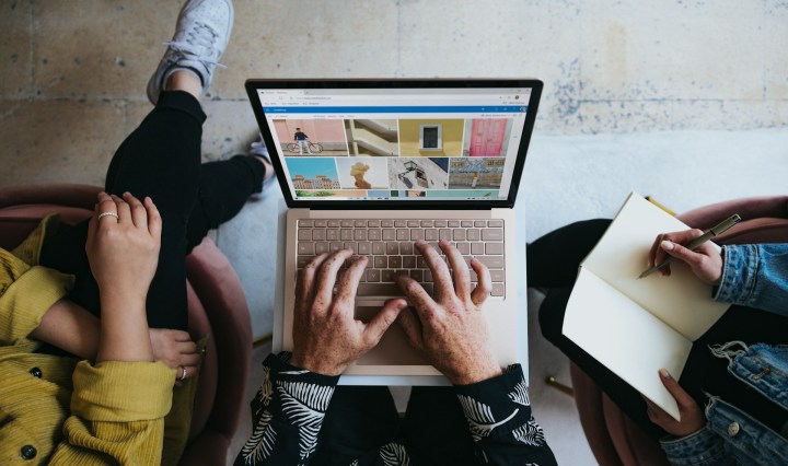 Aerial view of three sets of hands working on a laptop