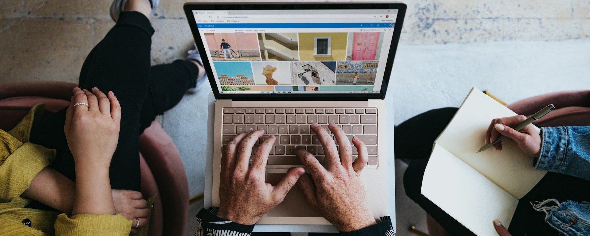 Aerial view of three sets of hands working on a laptop