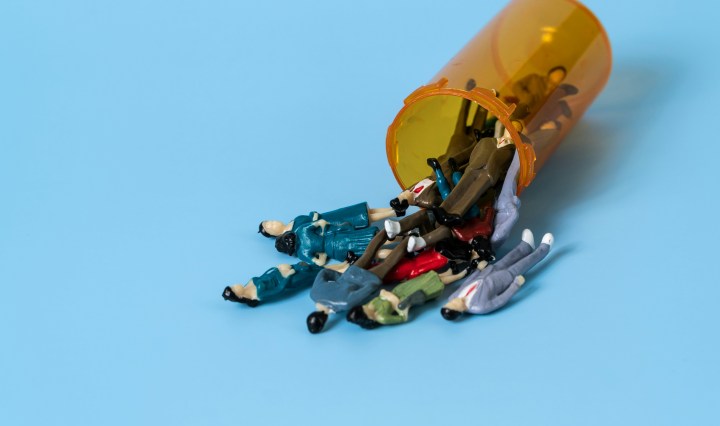 Miniture model people spill out of a pill bottle