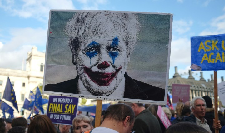 Protesters carry a plackard with Boris Johnson's face made to look like The Joker