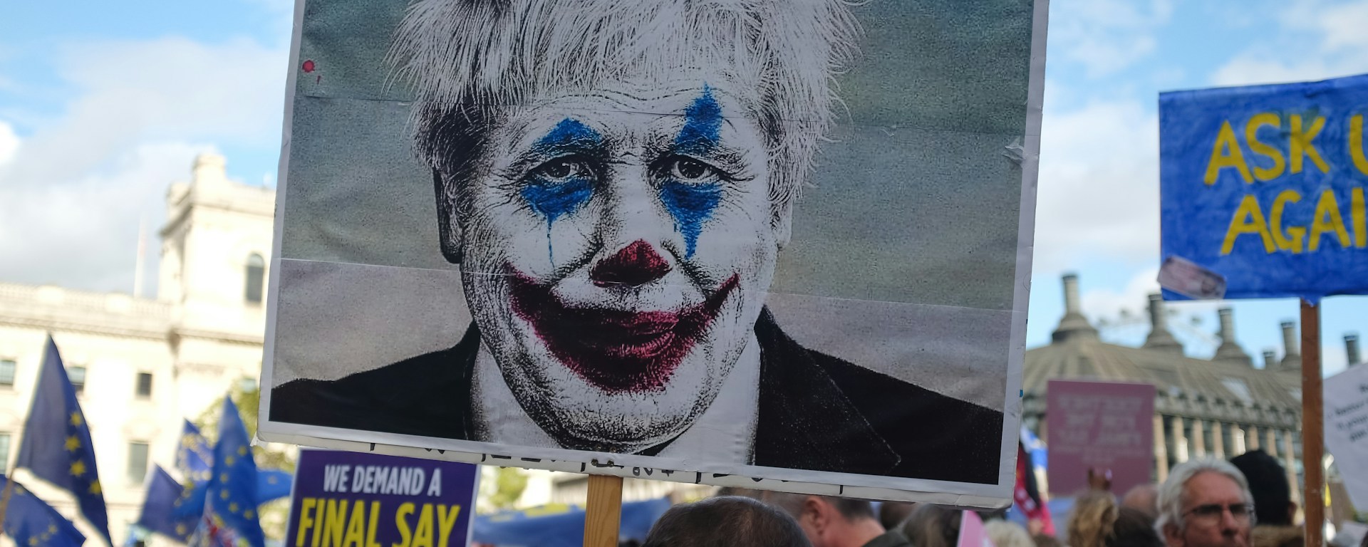 Protesters carry a plackard with Boris Johnson's face made to look like The Joker