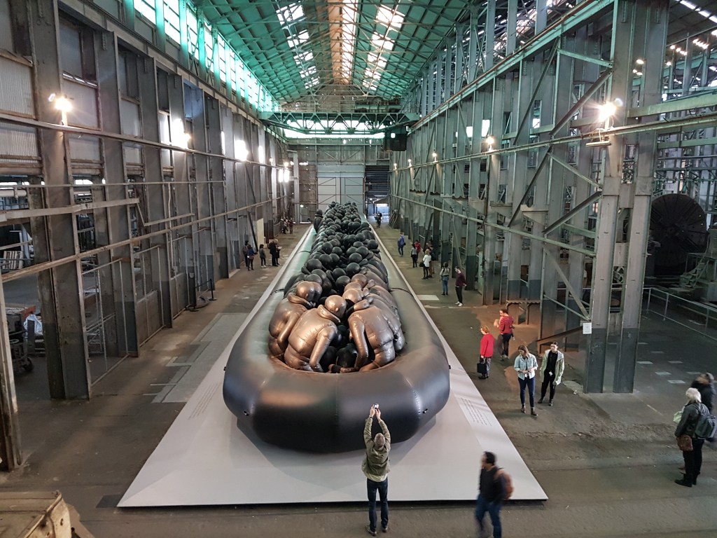 Peple reach their arms above their heads to take photos of the installation