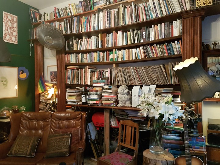 A leather couch and flowers in front of a large bookcase
