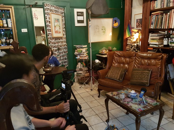 Camera crew and filming lights behind a leather couch