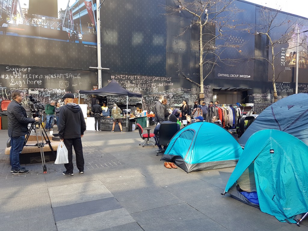 People stand beside tents in the middle of Martin Place