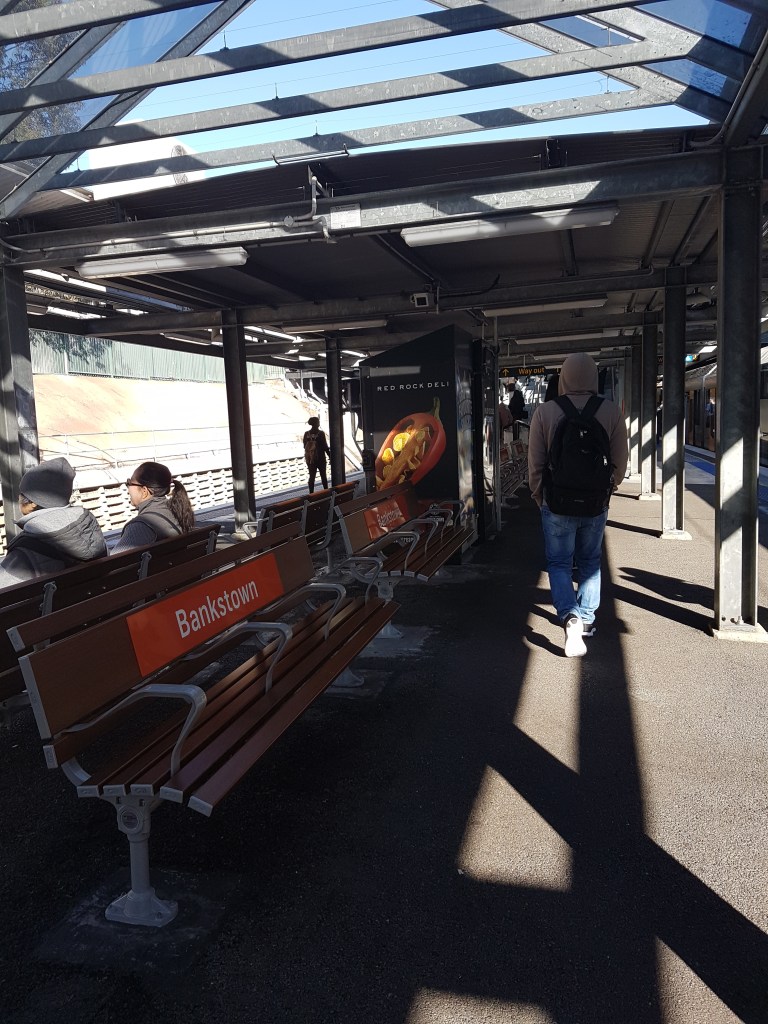 People sit and walk through Bankstown Train Station