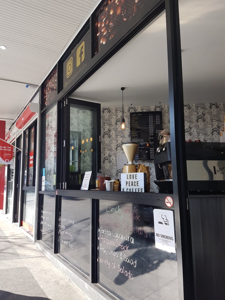 The front of a take-away coffee shop, with a sign that reads: Love, peace & coffee