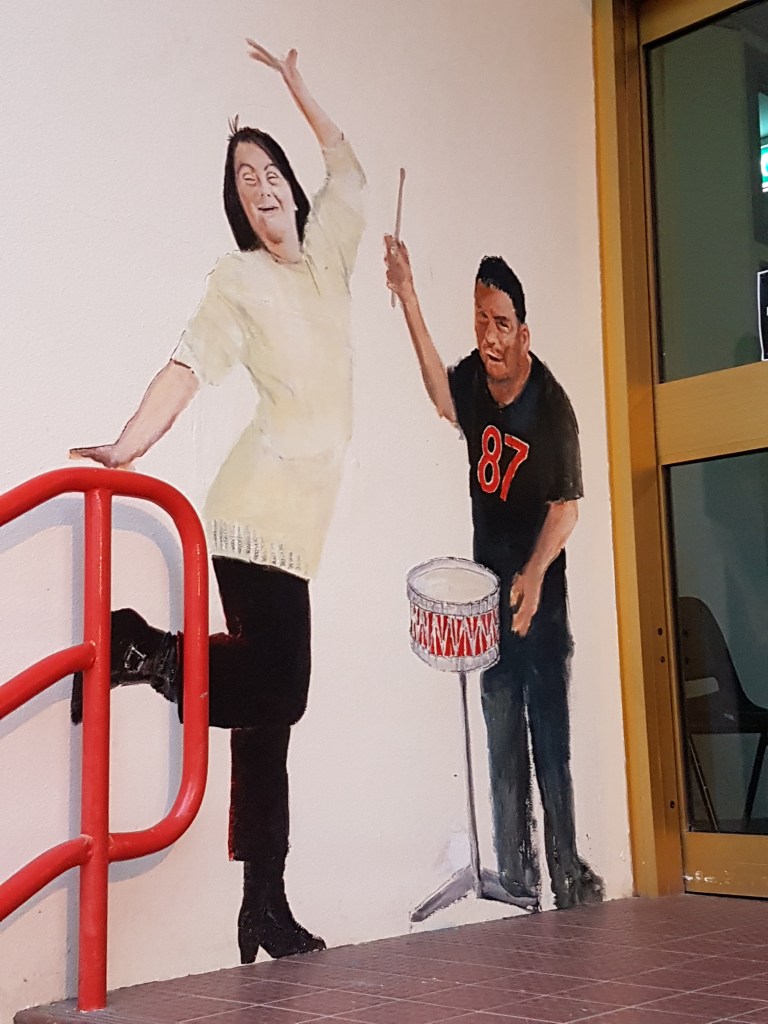 Street art outside a community organisation, showing people with disability singing and playing the drums