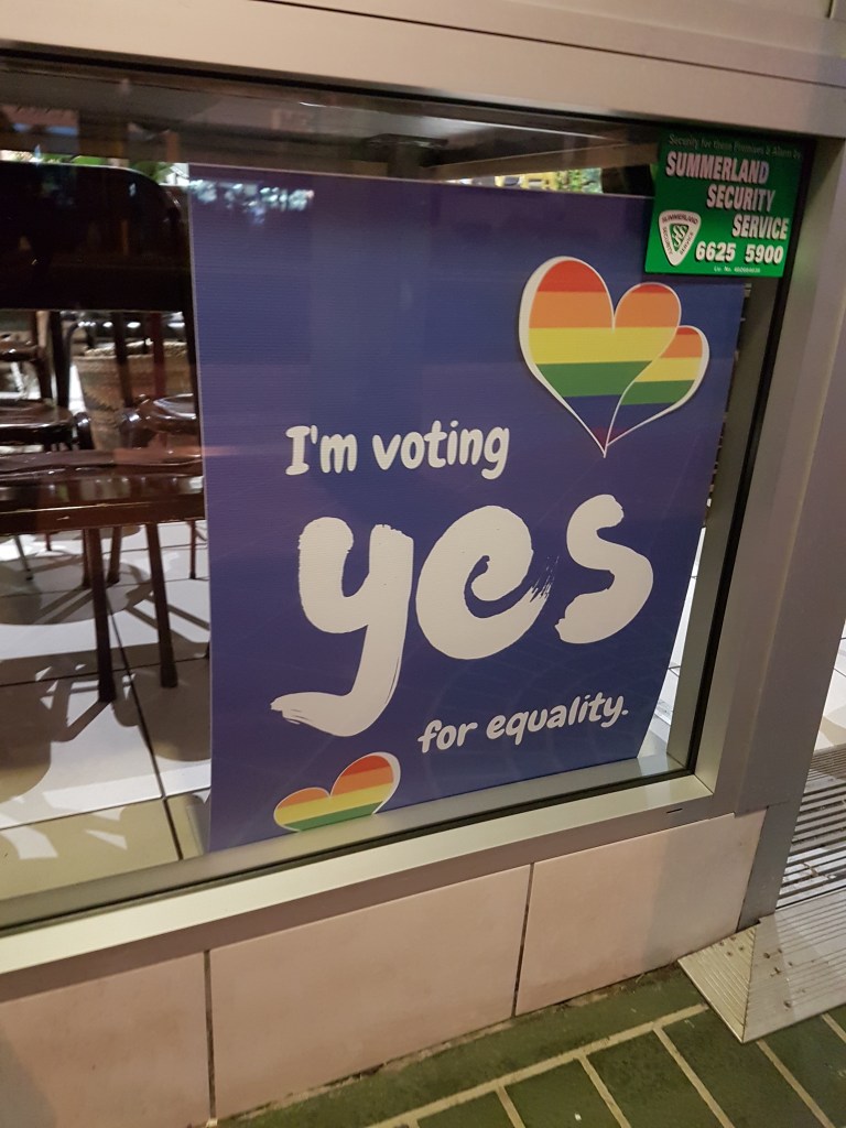 Poster on a shop window reads: I'm voting yes for equality" and the pride flag (Marriage Equality vote)