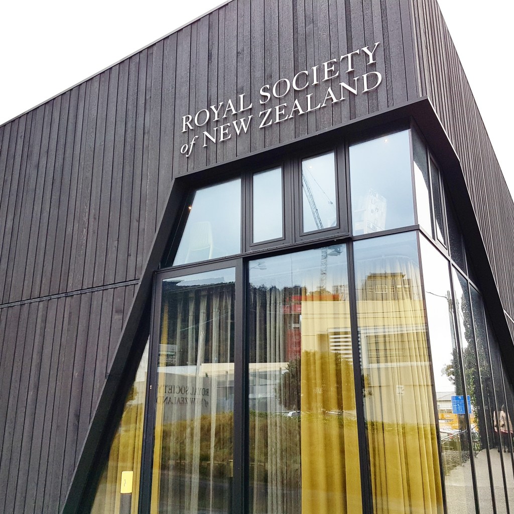 Outside of the Royal Society of New Zealand, a grey structure with tall windows