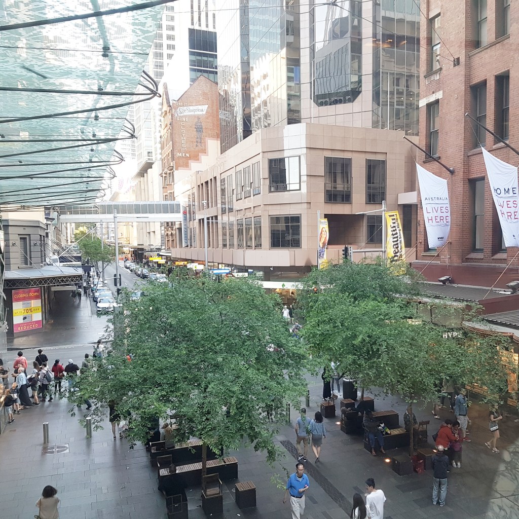 Aerial view of the mall in Sydney, showing people walking below a canopy of trees and buildings