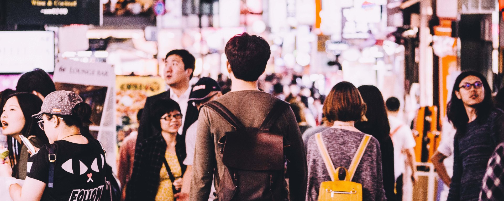 A person has their back to us as they walk through a busy city