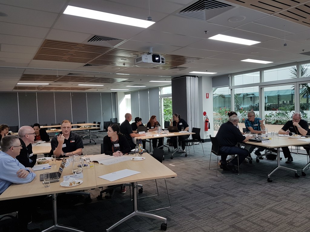 Tables arranged in groups of four show white peopel talking