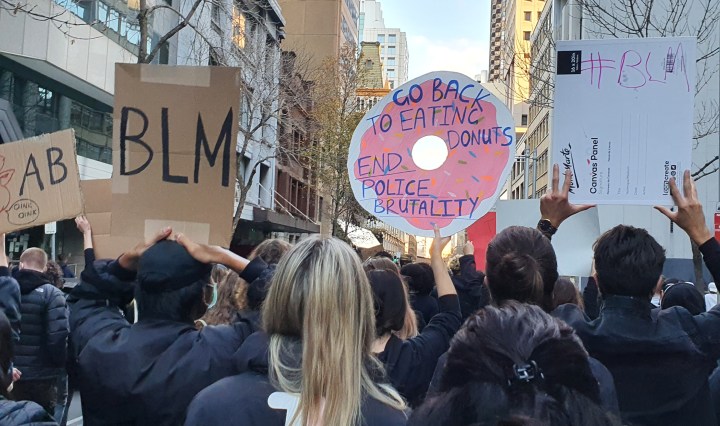 People march in Sydney holding signs that say "BLM" and "go back to eating donuts, end police brutality'