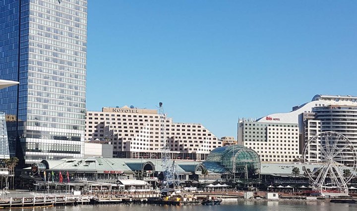 International Conference Centre ICC Darling Harbour, Sydney. Tall buildings along the water and a huge ferris wheel in the distance