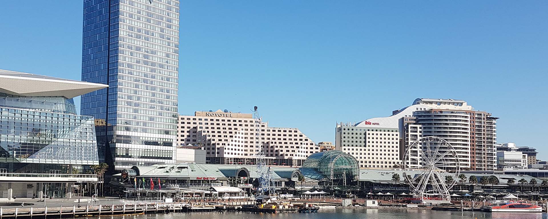 International Conference Centre ICC Darling Harbour, Sydney. Tall buildings along the water and a huge ferris wheel in the distance