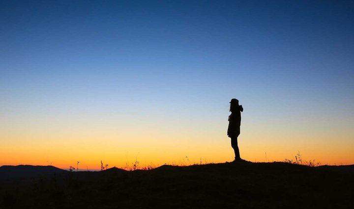 A person stands in the far horizon at dusk