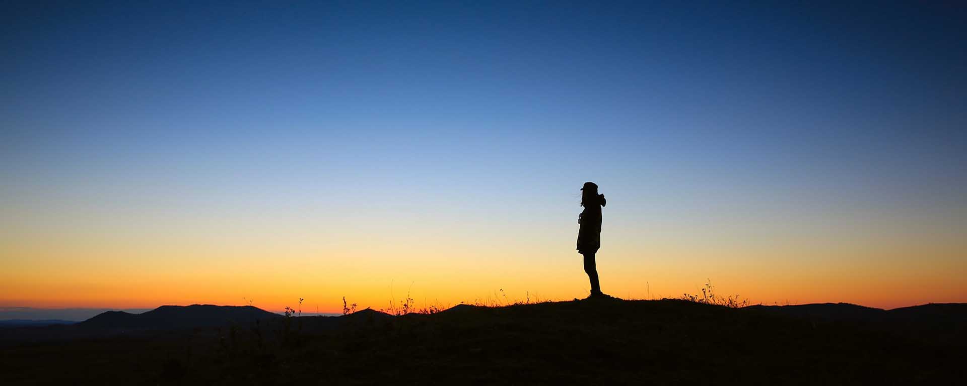 A person stands in the far horizon at dusk