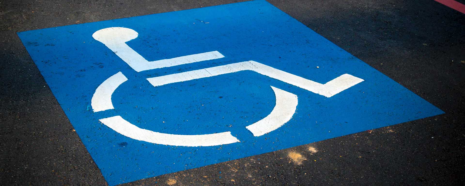 Disability parking sign on the road, showing a picture of a wheelchair