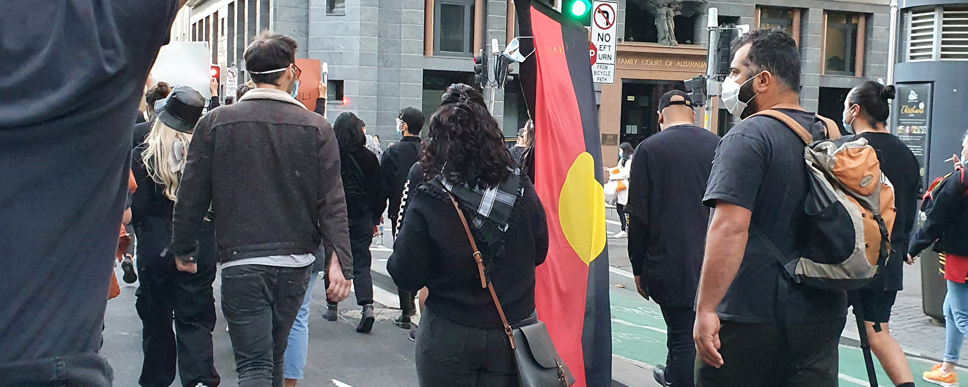 Protesters at the Stop Black Deaths in Custody march in Sydney. One man carries the Aboriginal flag