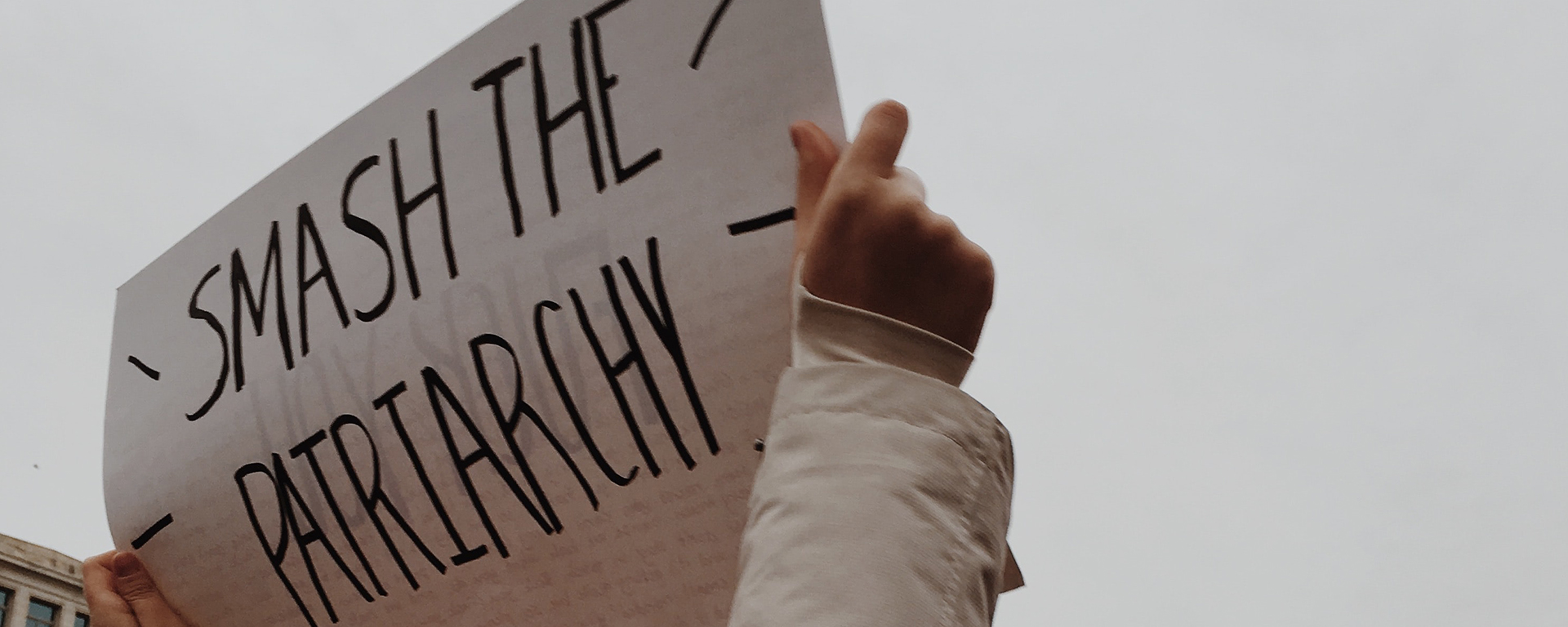 Close up of a child's hands holding up a protest sign. It says: Smash the patriarchy
