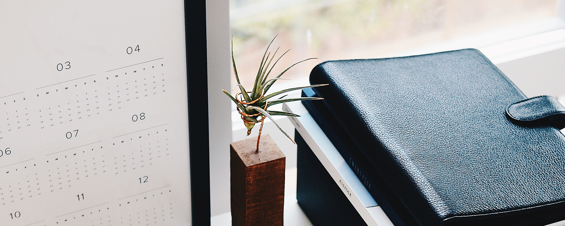 A calendar on a desk with a journal and plant