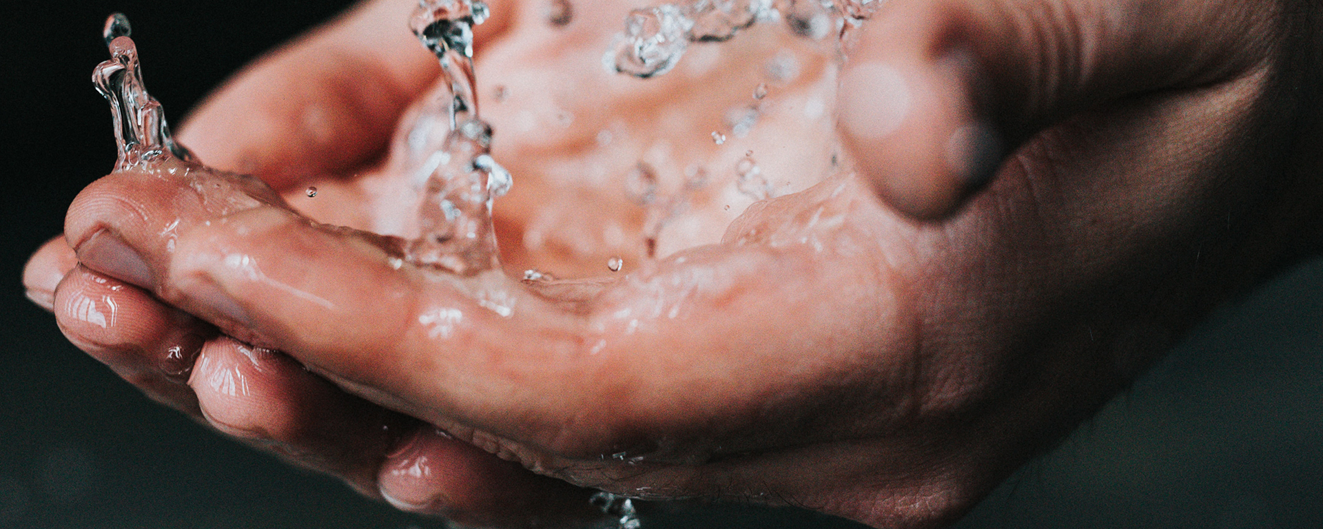 Close-up of white person's hands over running water