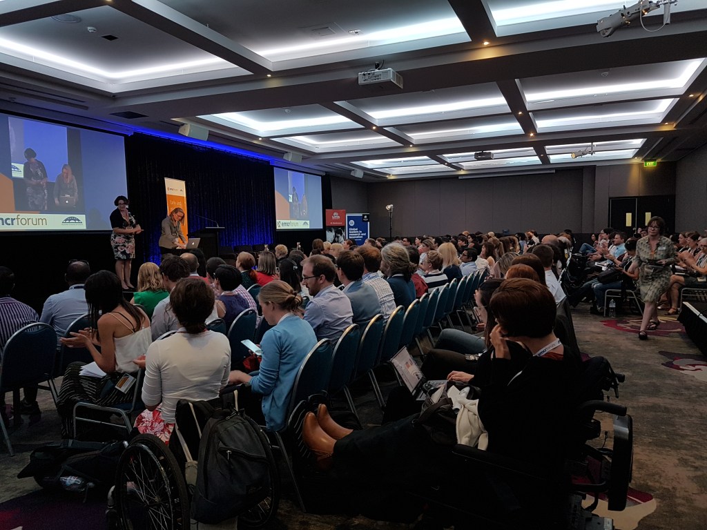 A large lecture theatre is full of people