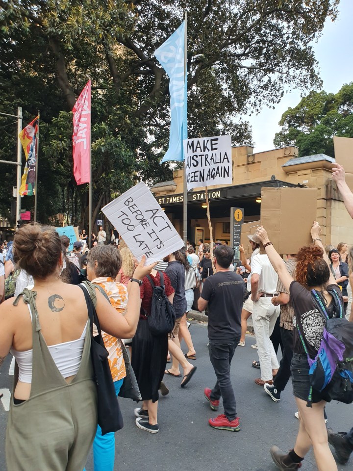 Protesters march in Sydney. One sign reads: Make Australia green again. Another sign reads: act before it's too late