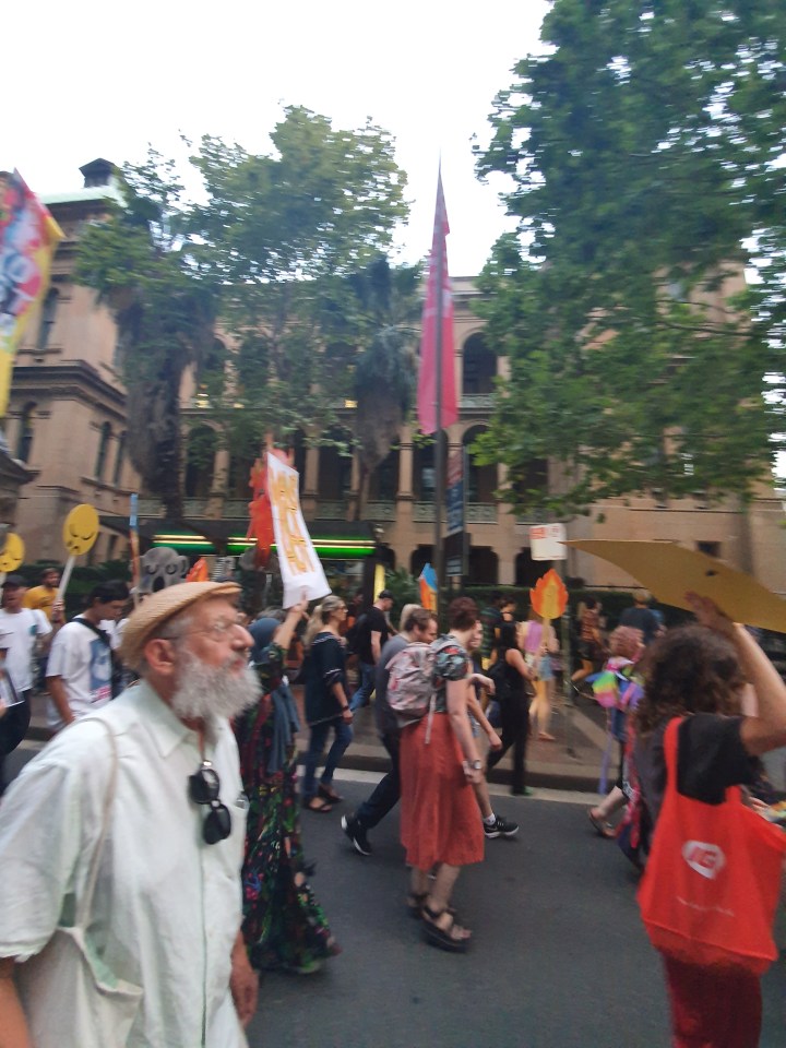 Protesters march in the Sydney CBD. In teh forefront is an older man with a white beard
