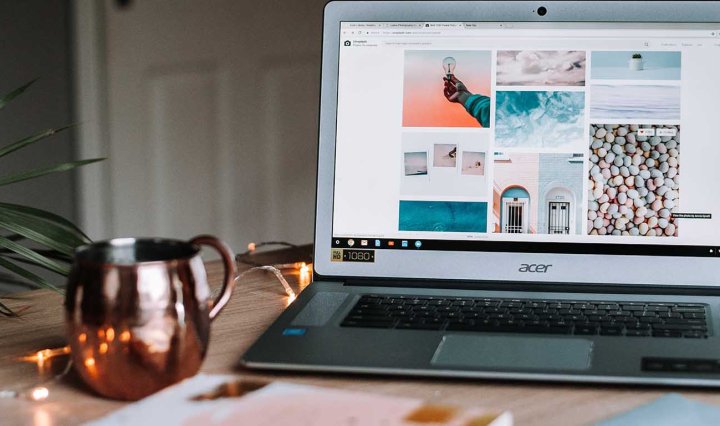 A laptop showing a photo blog sits on a table next to a coffee cup