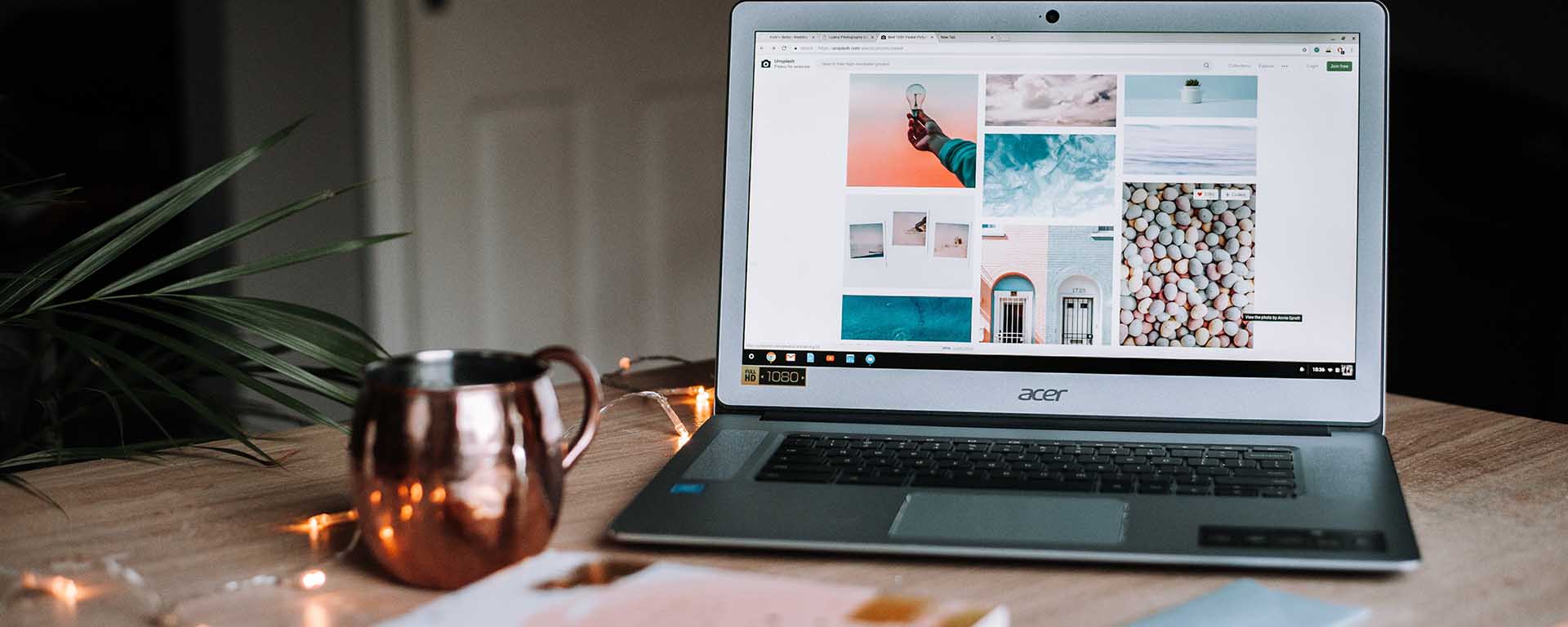 A laptop showing a photo blog sits on a table next to a coffee cup