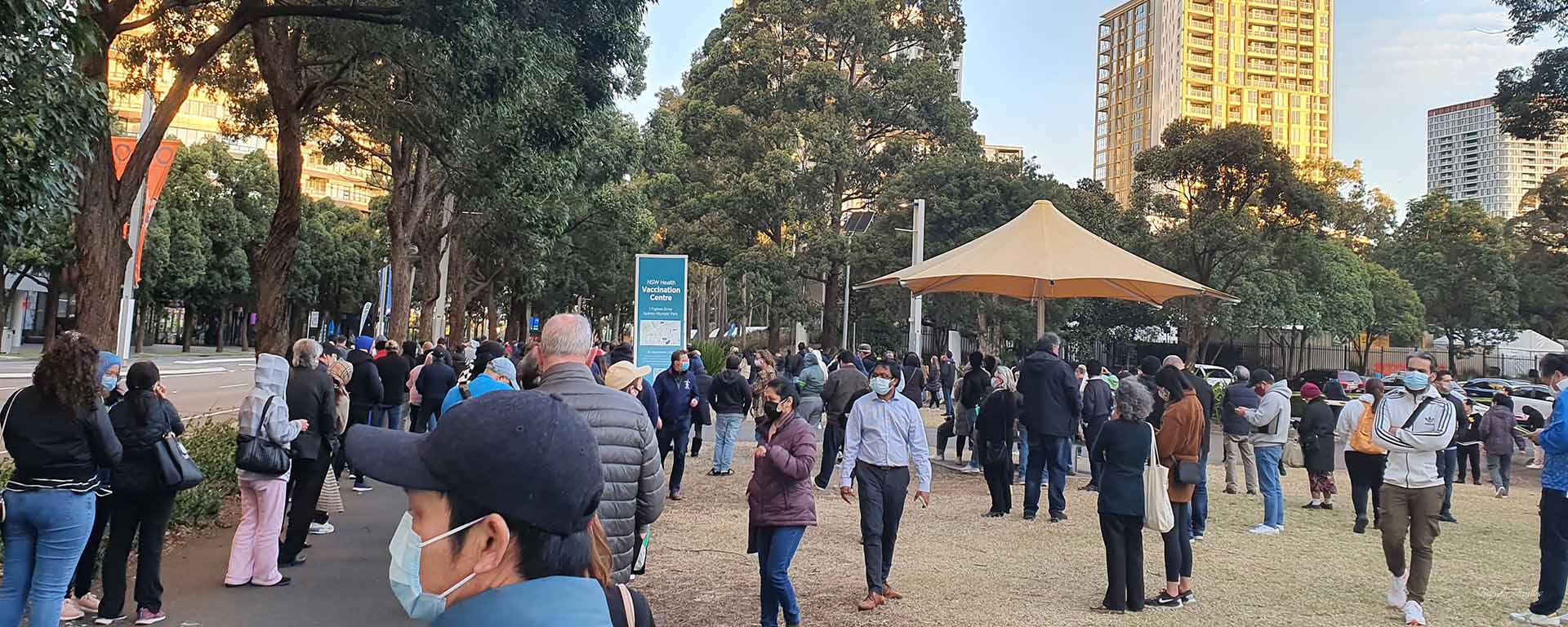 People in face masks line up in a large park