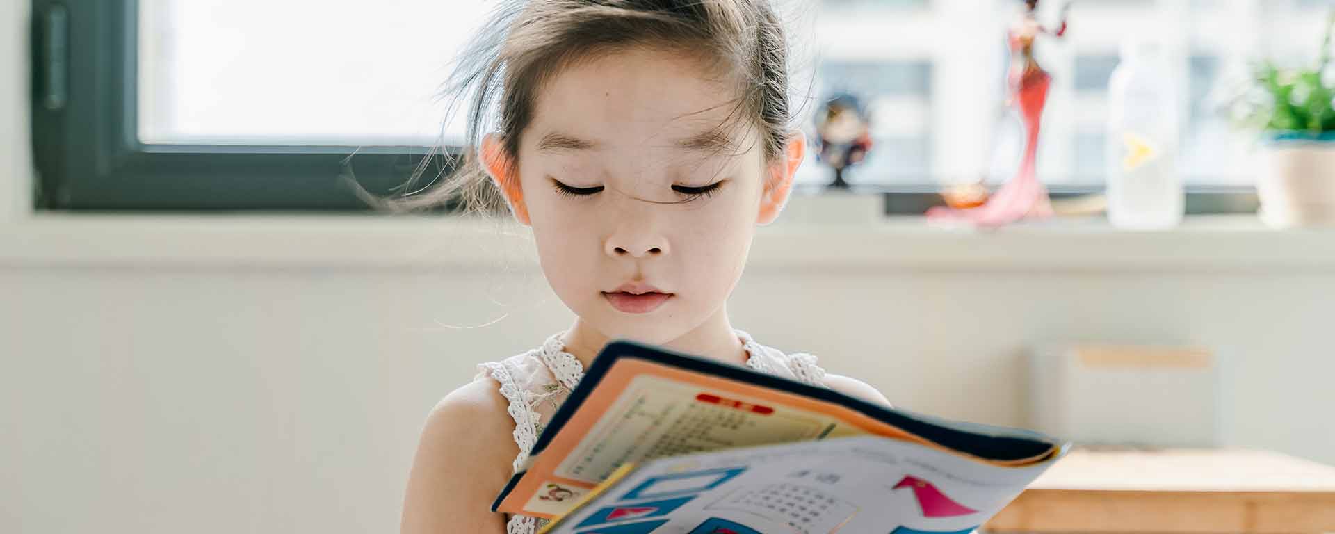 A young Asian girl is reading a magazine