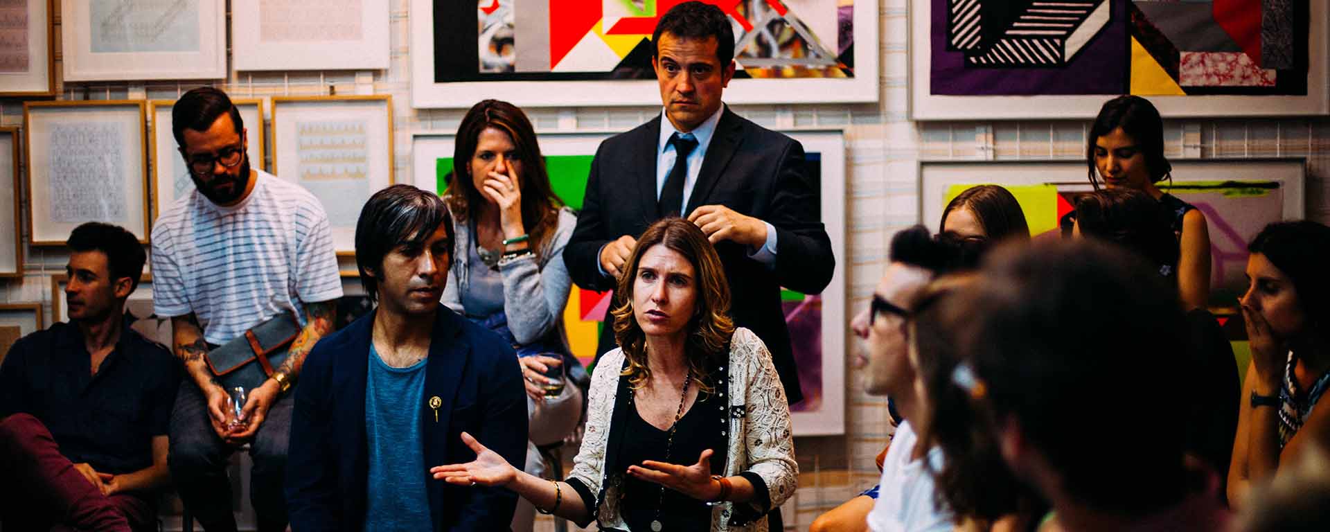 A room full of majority white people are listening to a woman speak about something seemingly serious