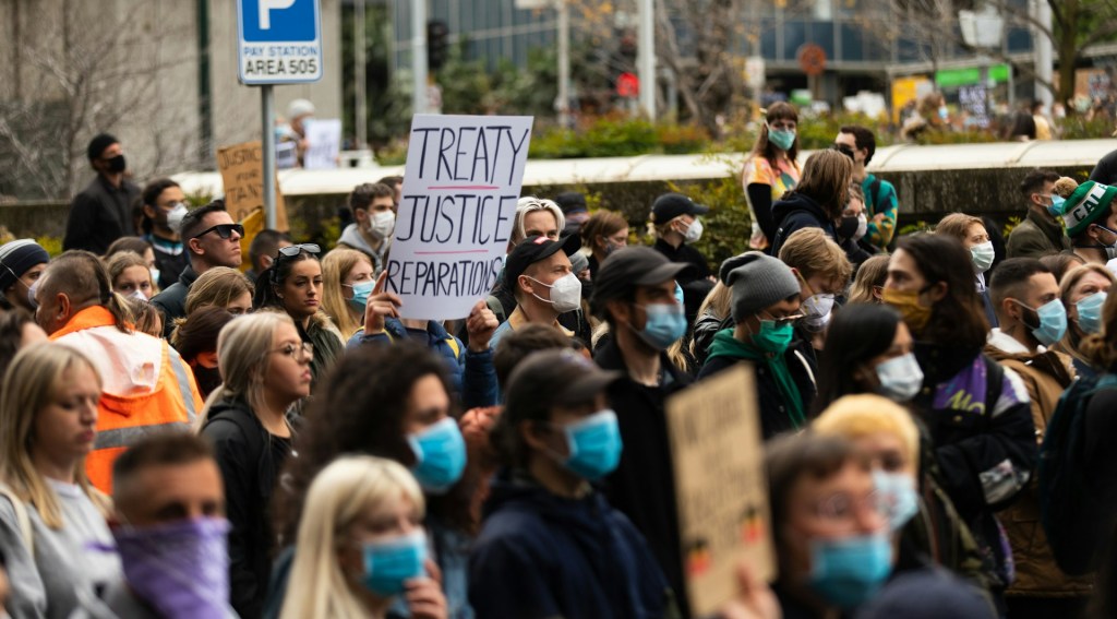 Protesters in Australia carry signs saying: Treaty, Justice, Reparations
