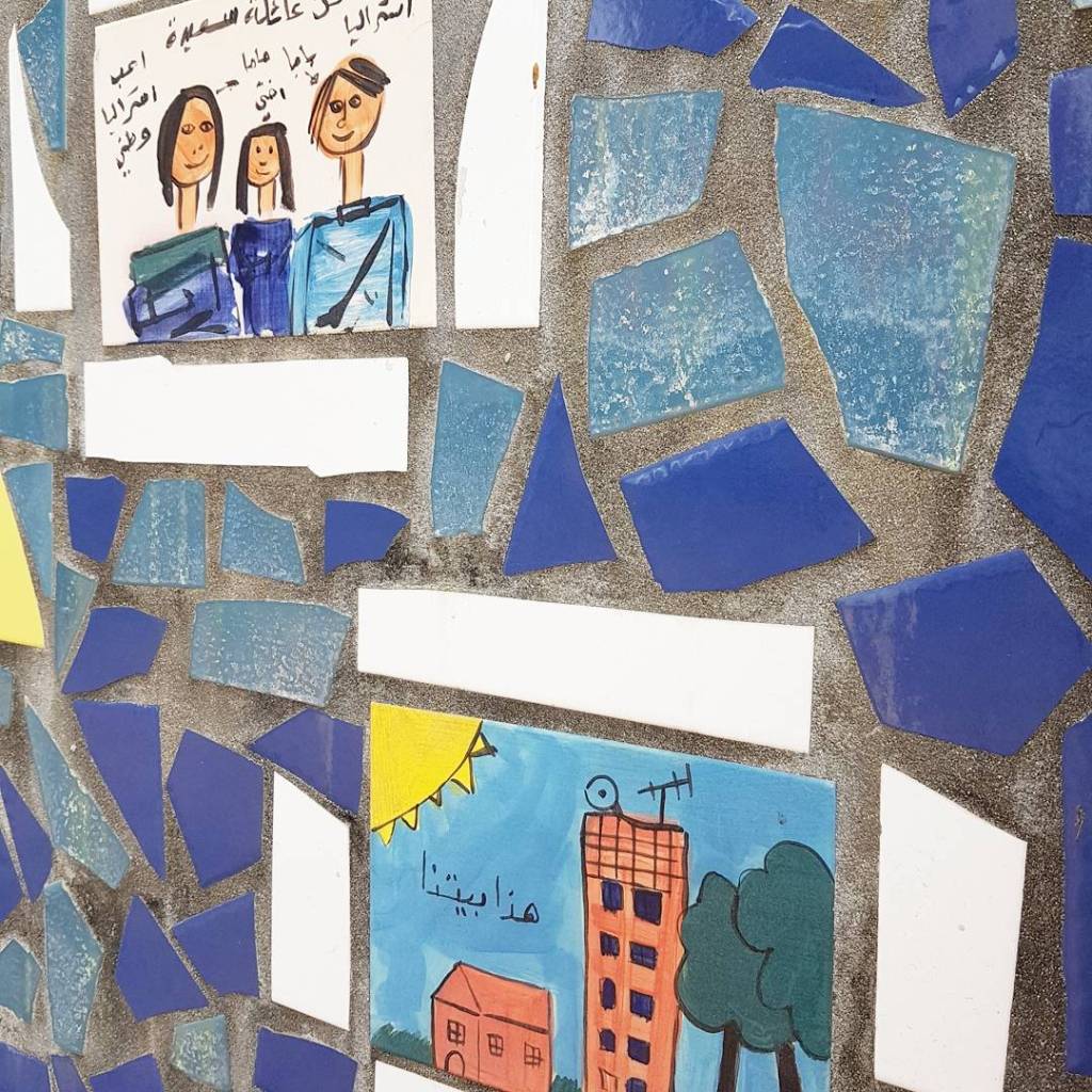 Mural with drawings by children, showing their families and homes
