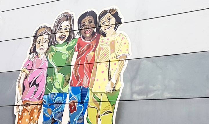 Drawing on side of building shows children hugging one another and smiling
